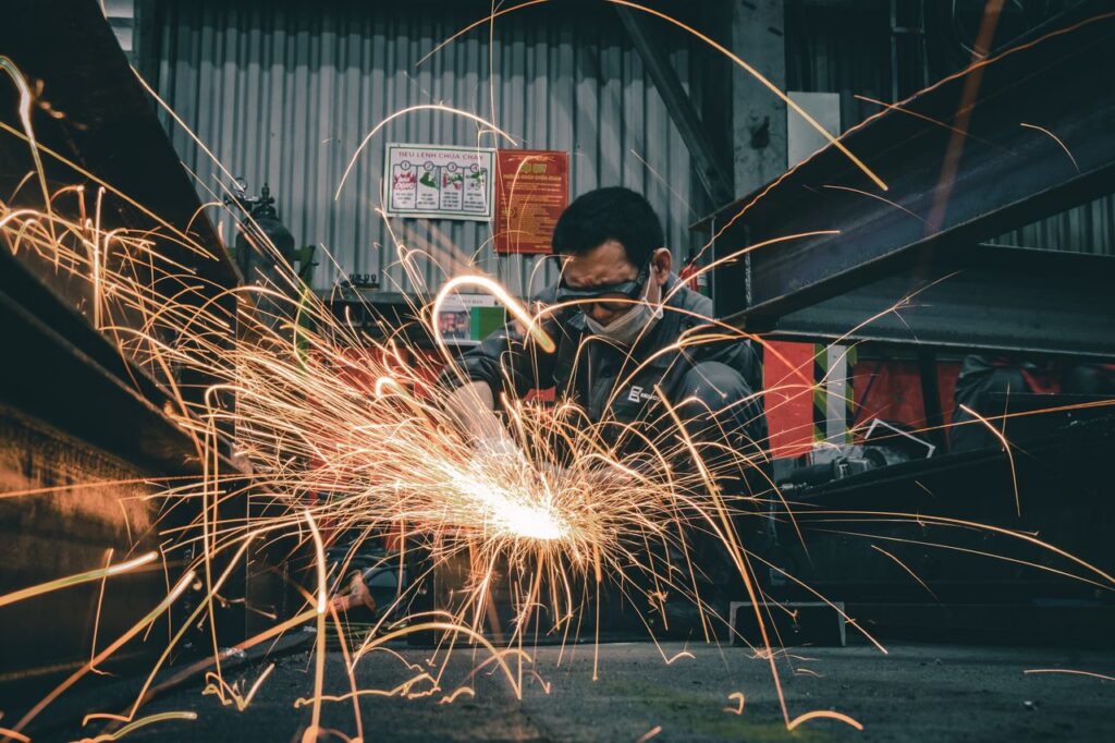 Focused welder creates vivid sparks while working with metal indoors, showcasing skill and industry.