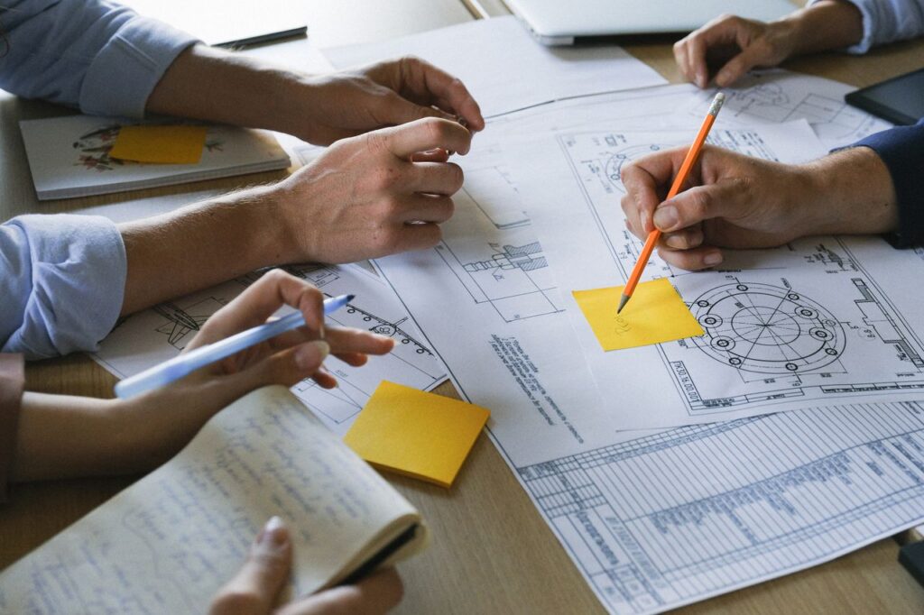 Senior Pilot Management de transition. Crop anonymous coworkers sitting at table with documents and discussing project during brainstorm in light office in daytime