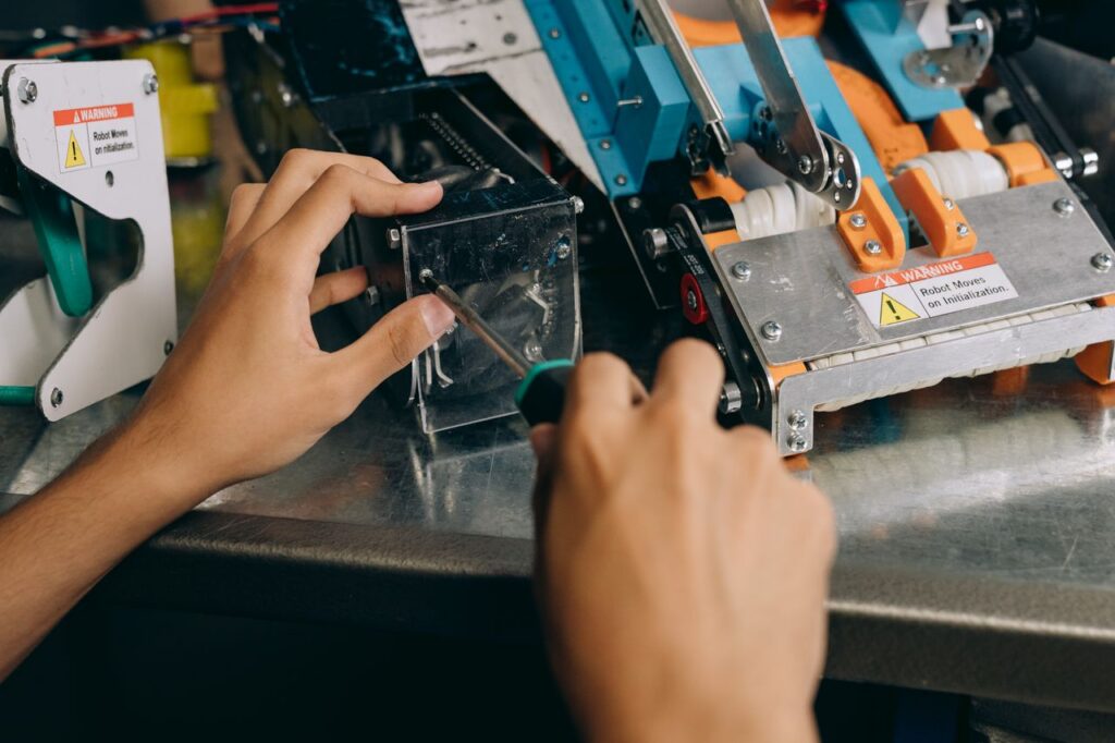 about-us-img Hands of a technician repairing robotic machinery with precision tools on a workbench.